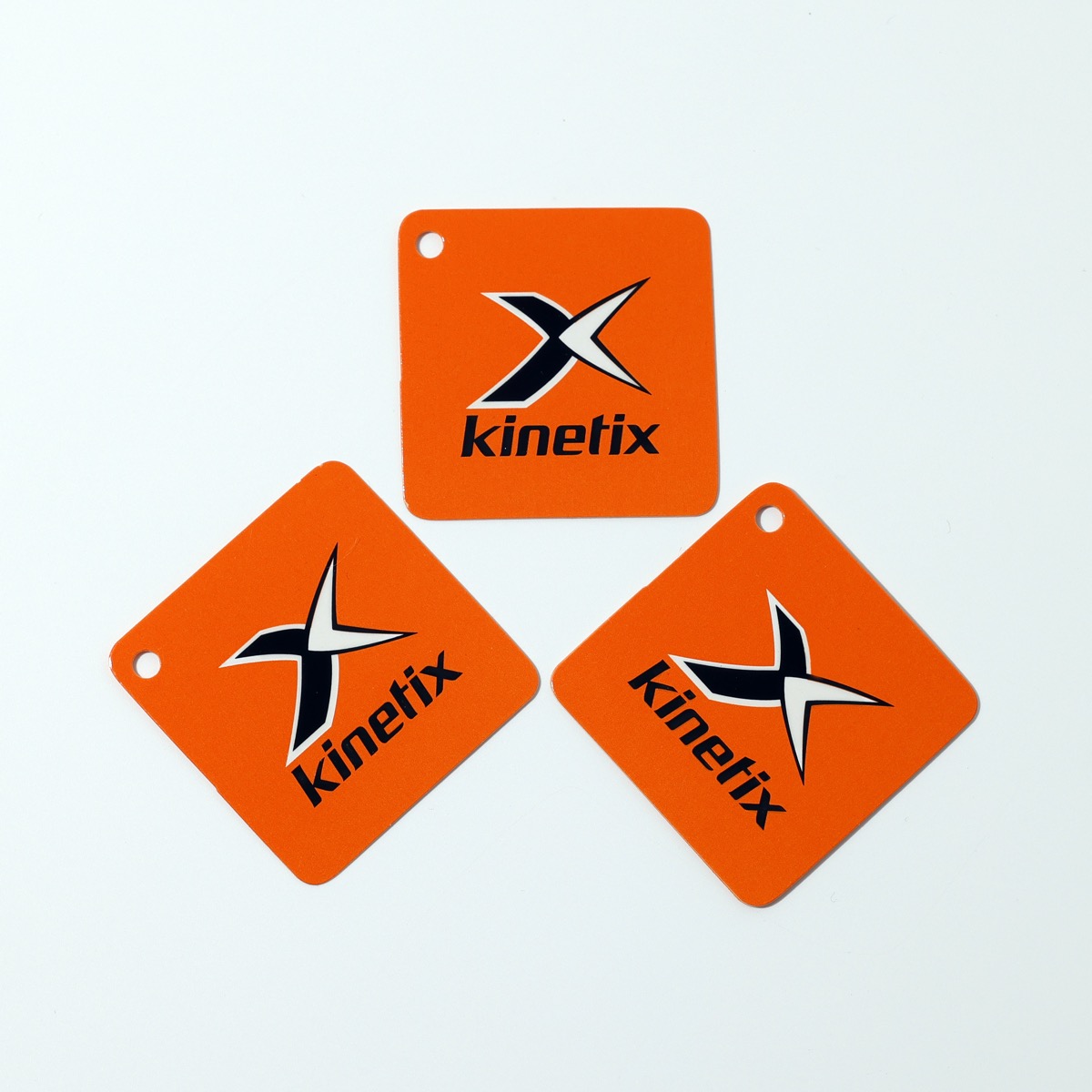 Kinetix sportswear — orange diamond hang tags with two-color logo print and drill hole