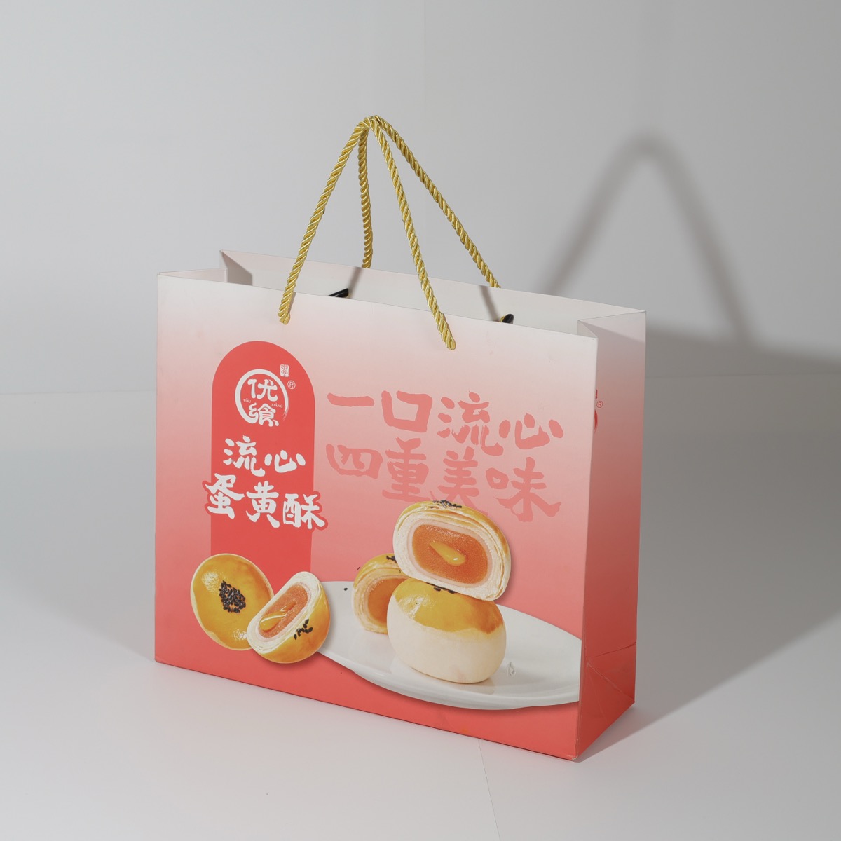 You Chan 优馋 lava egg-yolk pastry — gradient retail gift bag with rope handles and food photography print